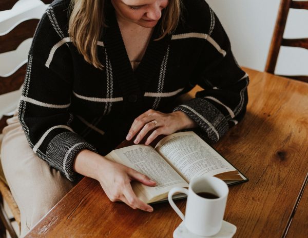 woman sitting at a table reading a book