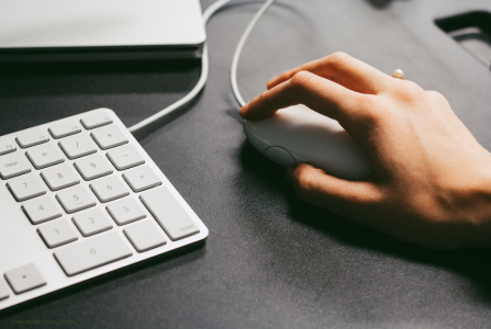 a hand using a mouse next to a keyboard