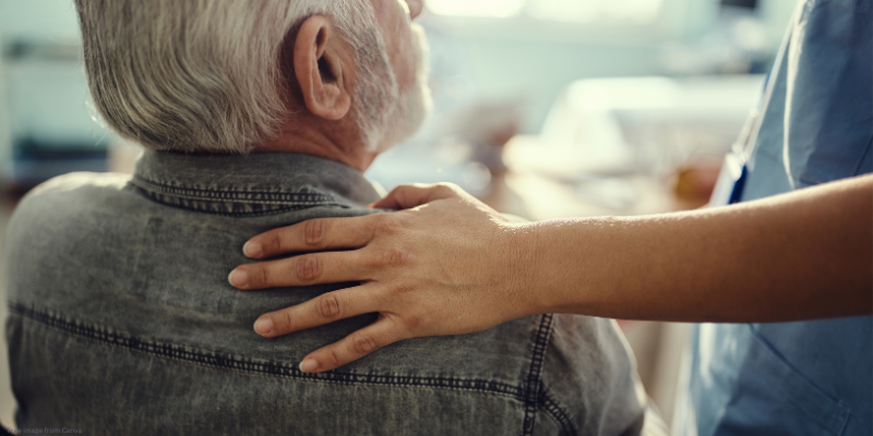 man sitting with hand on shoulder