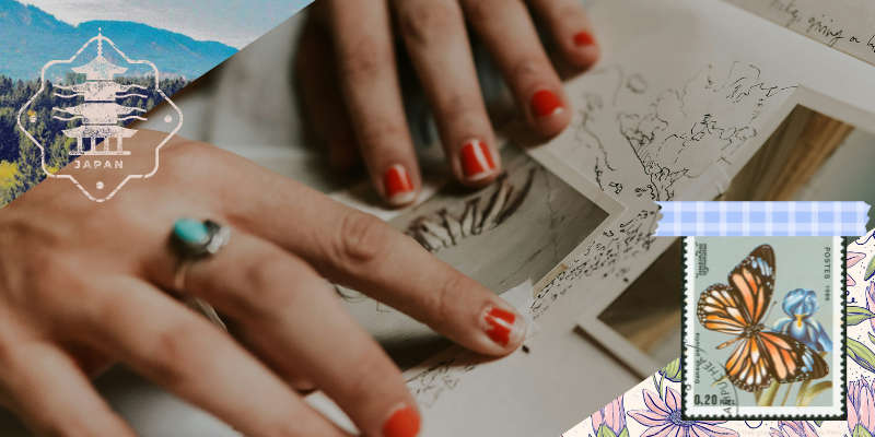 person taping picture into journal along with a travel stamp and vintage postage stamp