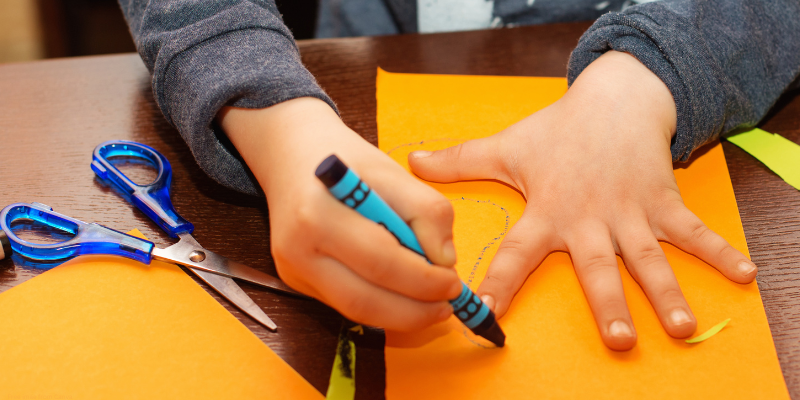 child tracing their hand on colored paper