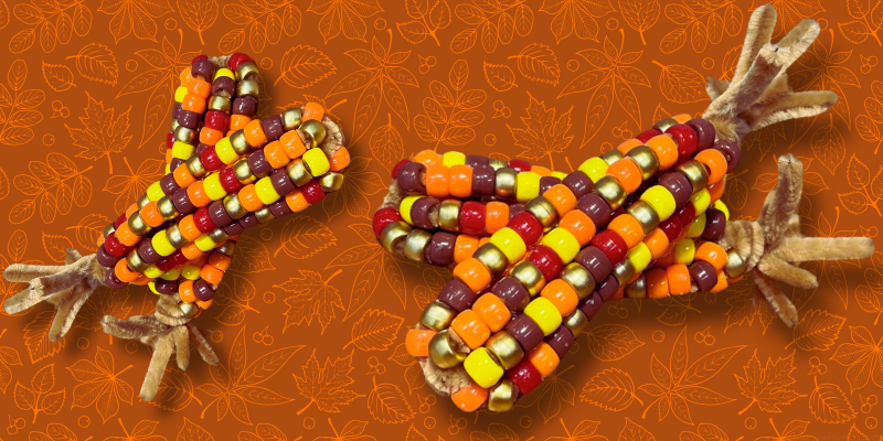 beaded fall corn with red, orange, yellow, brown, and gold beads, and brown pipe cleaners at the ends.
