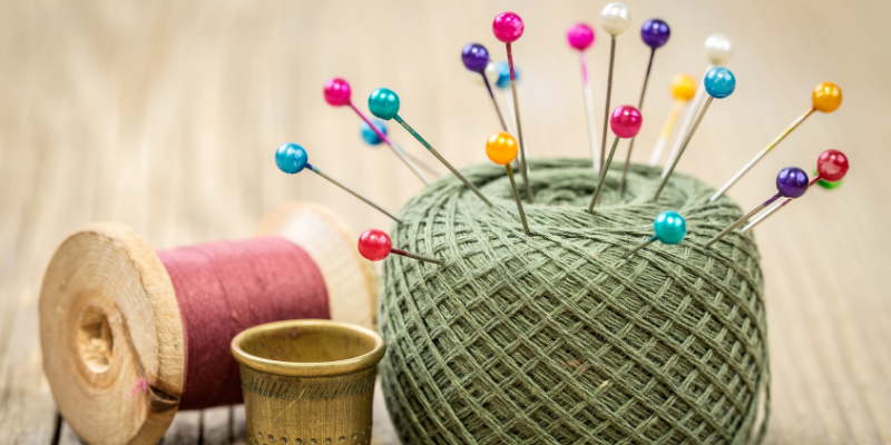 pin cushion with colored pins fr sewing, thread, and thimble
