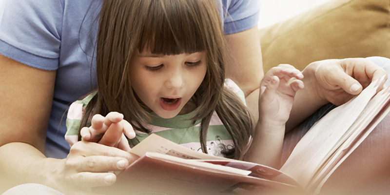 child reading a book on parent's lap