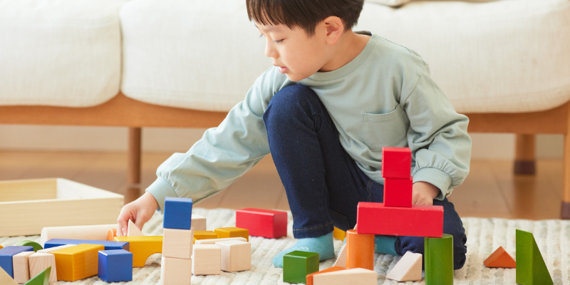 young child building a tower with colorful blocks