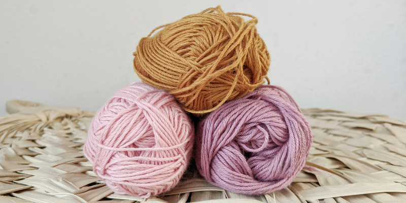 pink, mauve, and rust orange yarn balls stacked