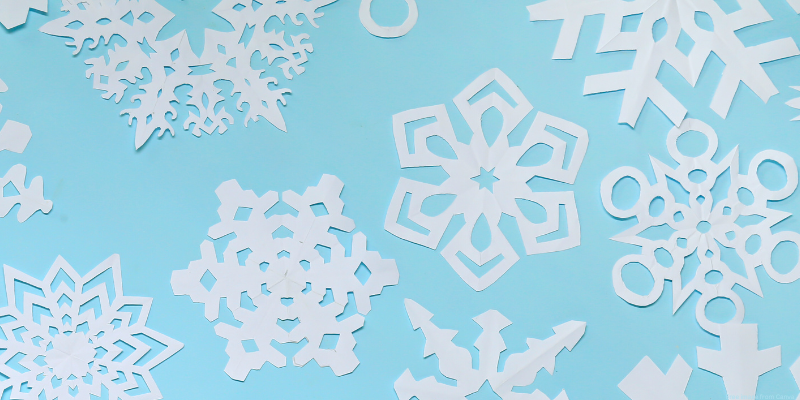 Intricately cut paper snowflakes on a light blue background.