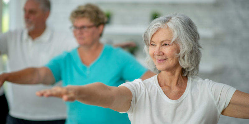 Elderly adults, stretching with arms extended, working on their balance