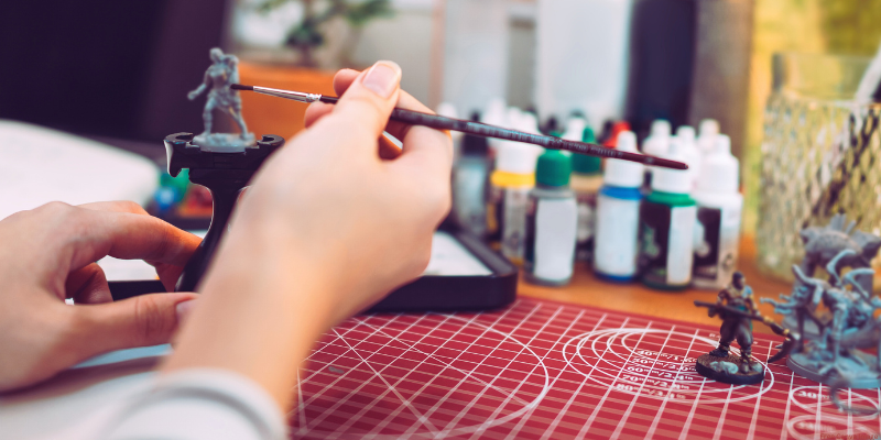 close-up image of person painting a mini figurine for tabletop game