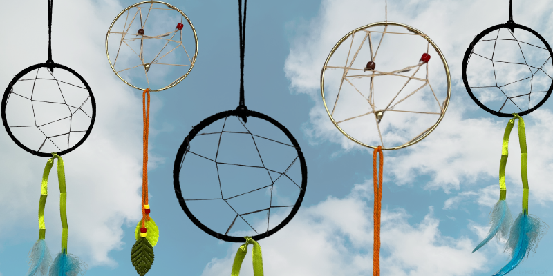 macrame hoops with string intertwined and ribbon and string hanging from it with feathers, with cloud background