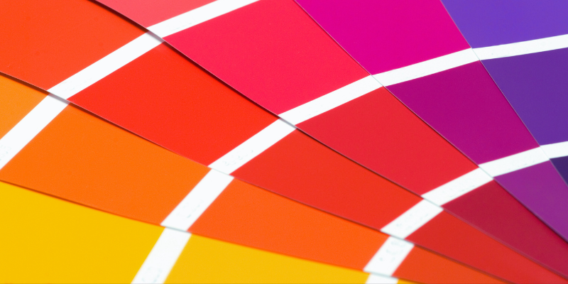A fan of paint swatches displaying a gradient from yellow to purple.