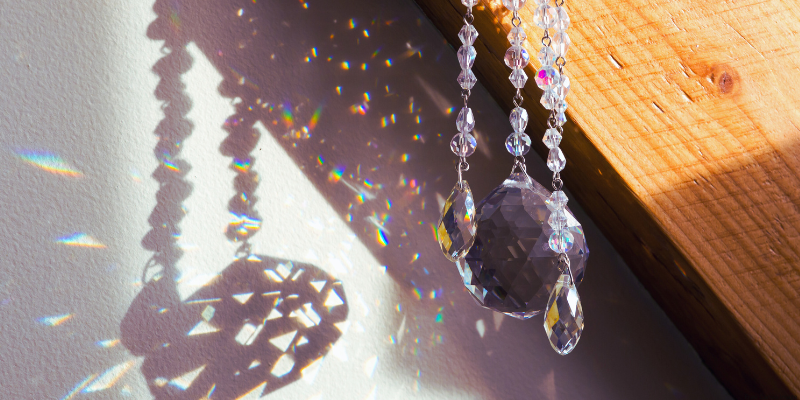 Faceted crystals hanging, casting rainbow patterns on a wall.