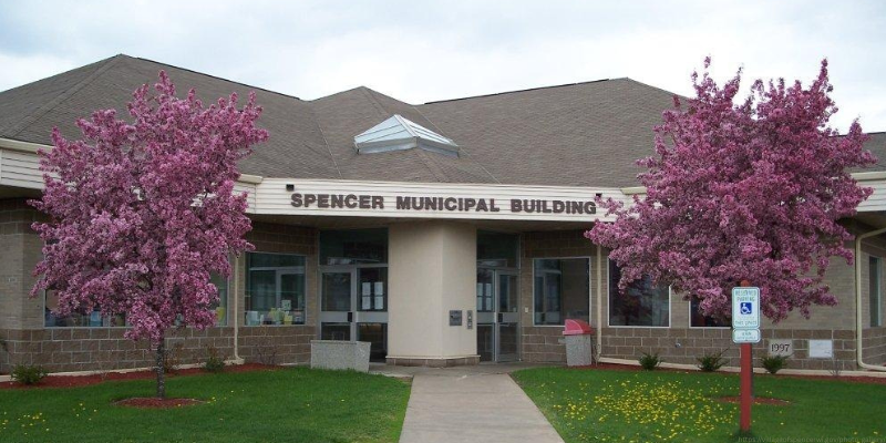 Front of Spencer Municipal Building with pink flowering trees and green lawn.