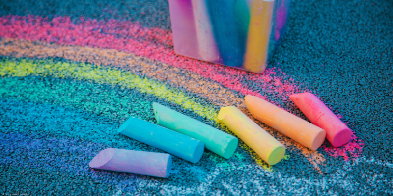 sidewalk with color rainbow drawn in chalk and chalk laying out
