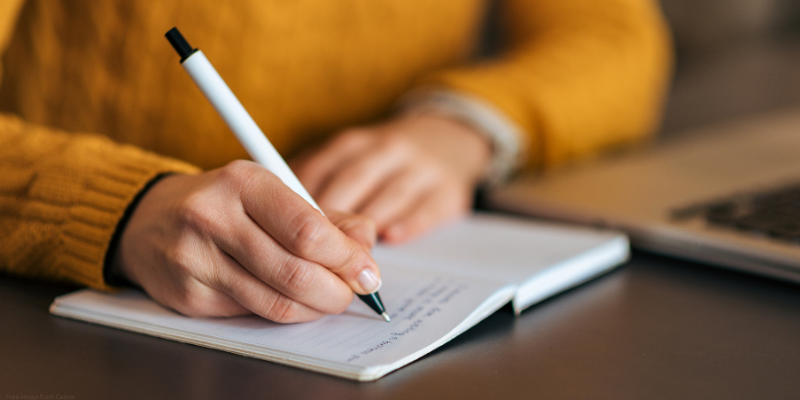 close up of hand writing in notebook