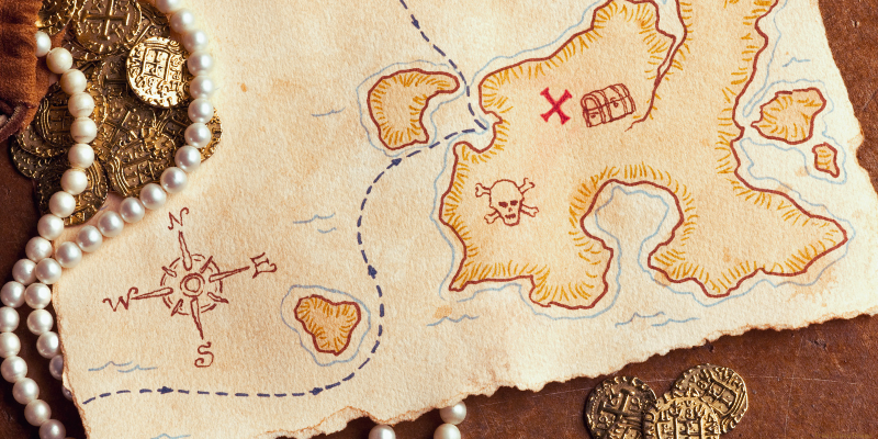 vintage looking photo of a treasure map, jewelry, and gold coins