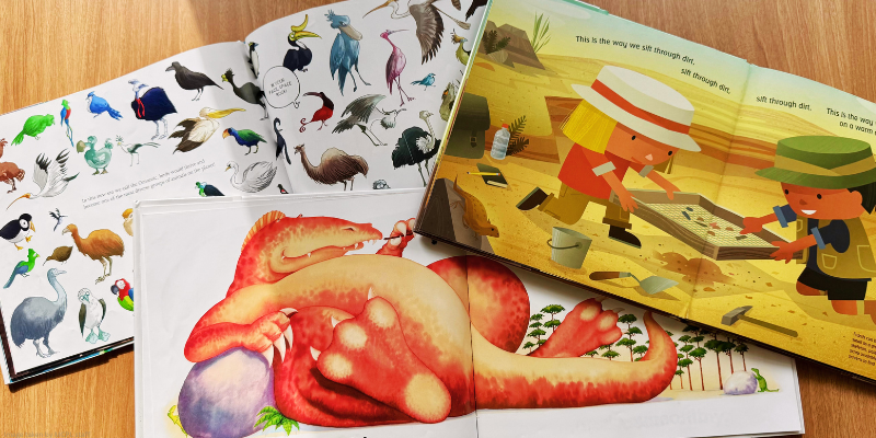 Open children's books with illustrations of birds, a dinosaur, and child archaeologists