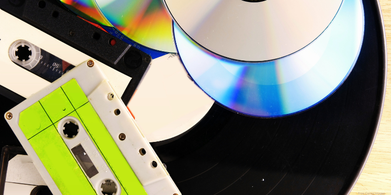 vinyl record, discs, and cassette tapes on a table